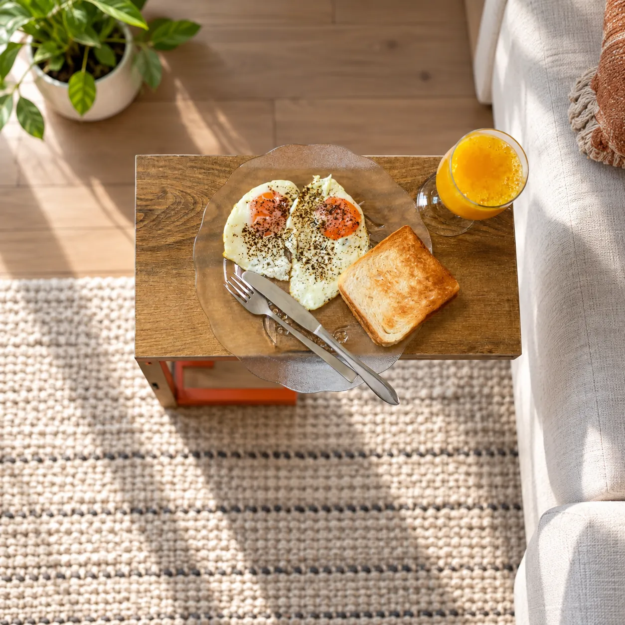 c shaped side table Top view of a C-shaped side table holding a breakfast plate of eggs and toast with orange juice beside a sofa
